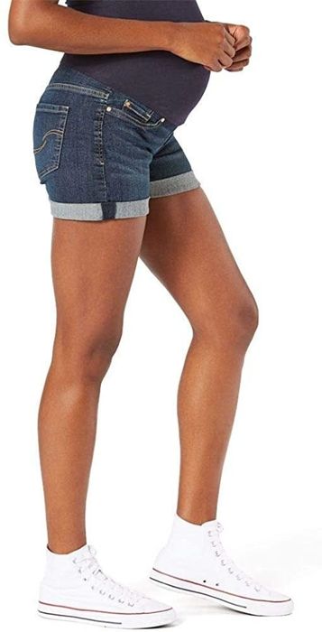 model wearing dark-wash cuffed maternity shorts with back pockets