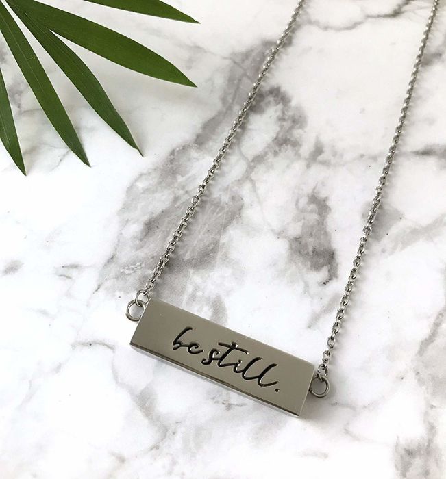 A necklace engraved with 'be still,' featuring a discreet spot to hold a diffuser pad for essential oils.