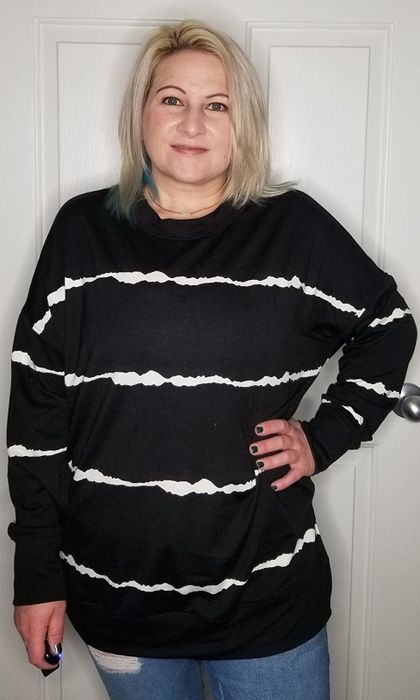 A reviewer dons a long-sleeve black top featuring white vertical squiggly stripes.