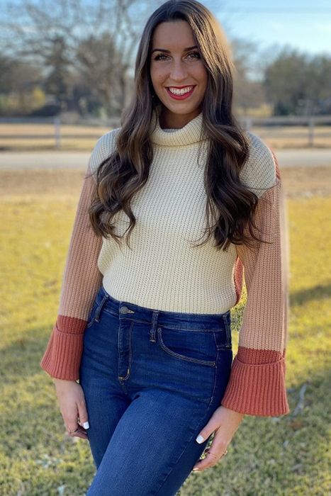 A reviewer wearing the sweater in white and orange color block
