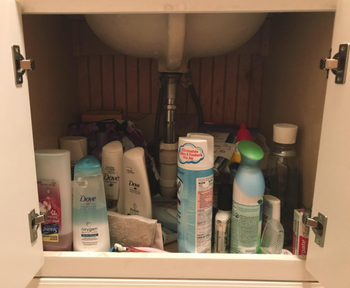 a reviewer’s photo of a cluttered mess of cleaning products under their bathroom sink
