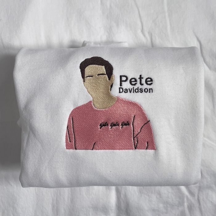 A white sweatshirt featuring an embroidered image of Pete Davidson's face.