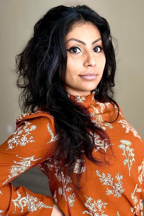 A reviewer wearing an orange floral mock neck blouse