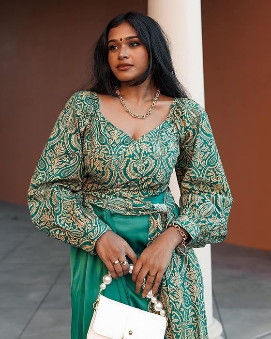 A model dressed in a stylish green long-sleeve surplice top featuring an intricate paisley pattern.