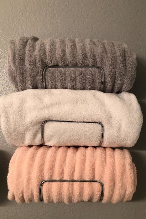 a reviewer’s photo of a chrome-colored towel rack neatly holding three rolled-up towels