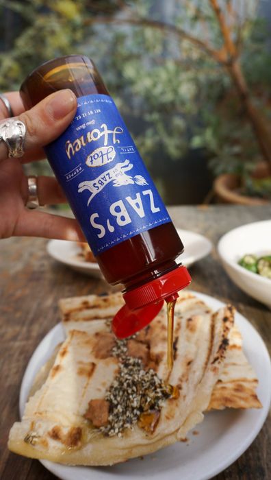 Model drizzling the hot sauce over food