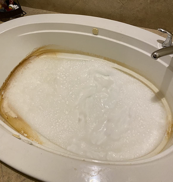 a reviewer’s jetted tub being cleaned with water and the cleaner, showing the dirt being removed