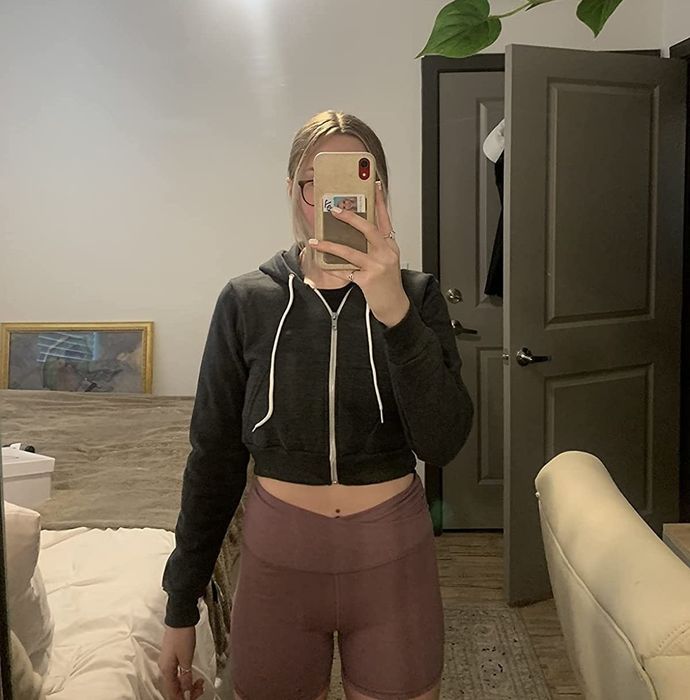 A reviewer captures a mirror selfie while wearing a black cropped hoodie.