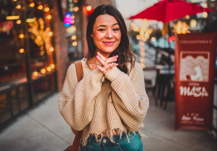 A reviewer showcasing the cropped sweater in a rich brown color.