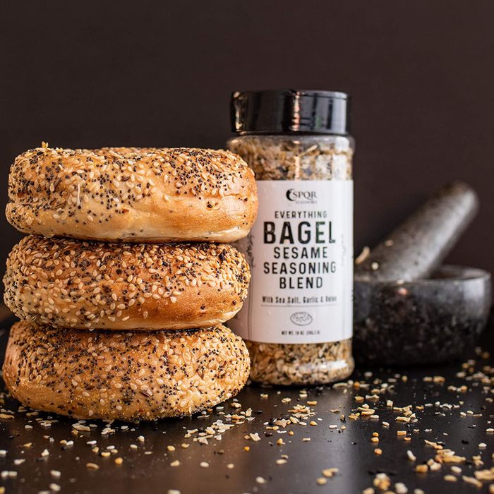 The seasoning in its container, paired with a stack of everything bagels