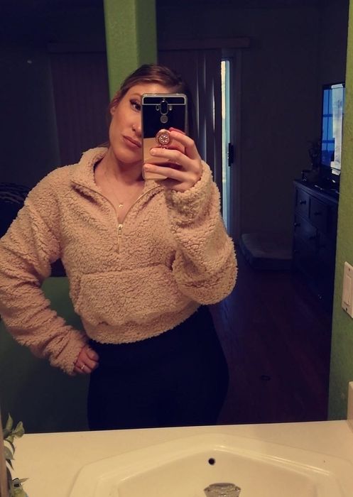 a reviewer taking a mirror selfie in a brown cropped fuzzy hoodie