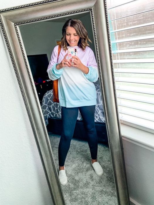 A reviewer sporting a color-blocked sweatshirt in shades of pink, blue, and white.