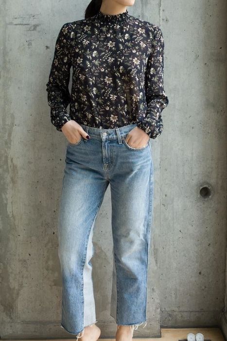 A reviewer wearing the dark blue floral top, tucked into denim jeans