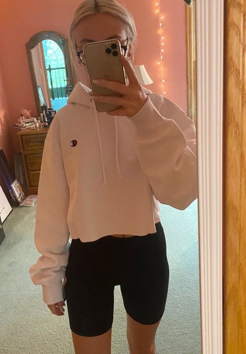 A reviewer takes a mirror selfie, rocking a white cropped hoodie.