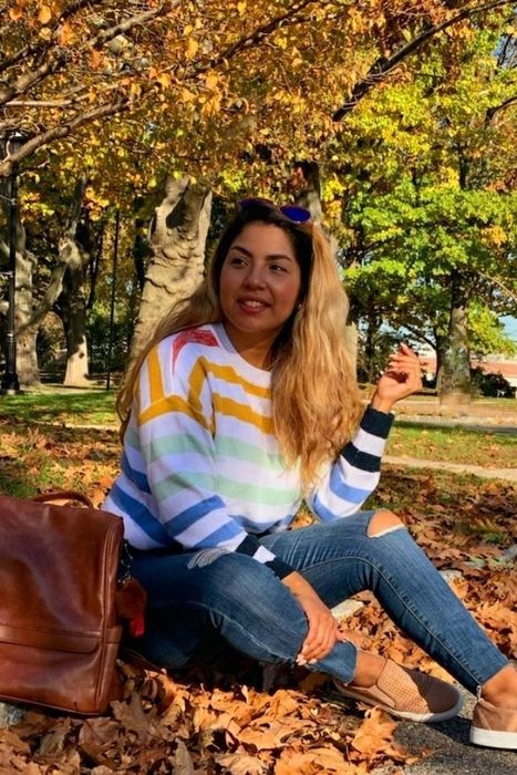 A reviewer pictured in a rainbow-striped pullover paired with jeans