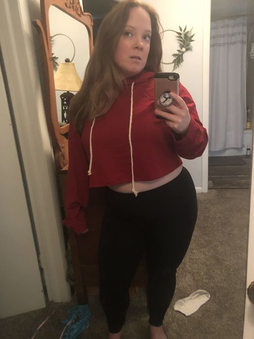 A reviewer snaps a mirror selfie while rocking a red cropped hoodie.