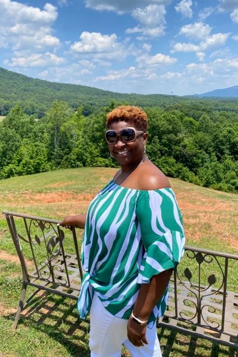 A reviewer wearing a green and white striped off-shoulder top with a tie-front design