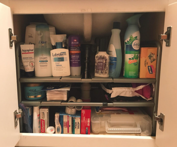 the same under-sink area now neatly organized with a shelving unit