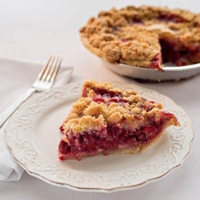 A slice of cherry crumb pie placed beside the rest of the pie