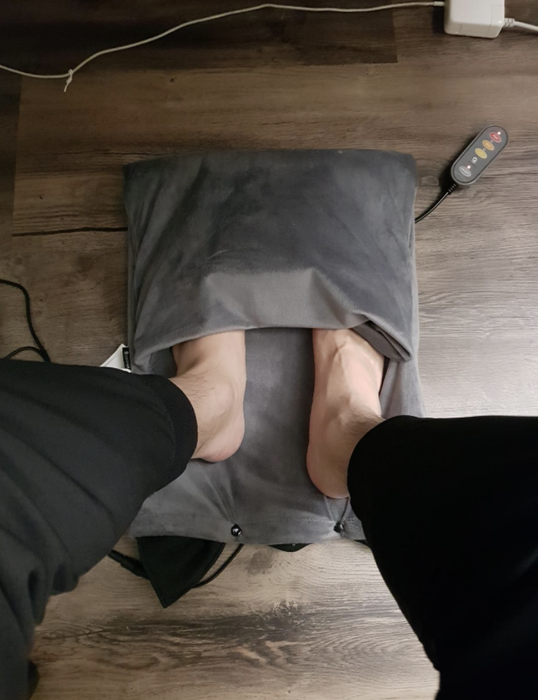 A reviewer demonstrates using a heating pad to warm their feet.
