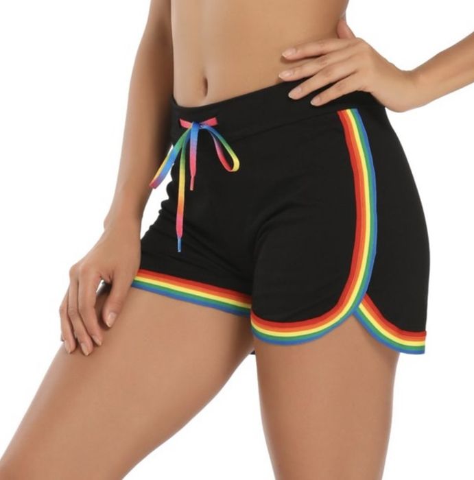 A person wearing black shorts with rainbow-striped detailing at the trim