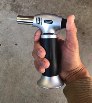 a reviewer holding the compact culinary blowtorch