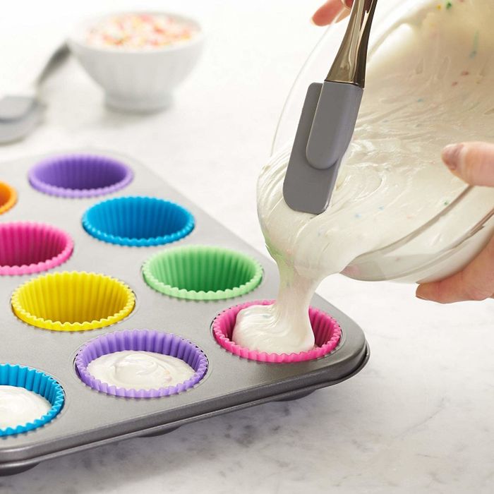 a model filling a muffin tin with batter using the silicone liner