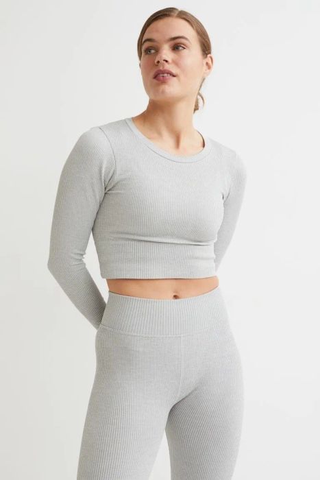 A model wearing matching gray ribbed seamless leggings and a long-sleeved crop top.