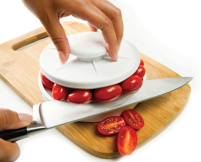A model demonstrating how to use the device to evenly slice tomatoes in half.