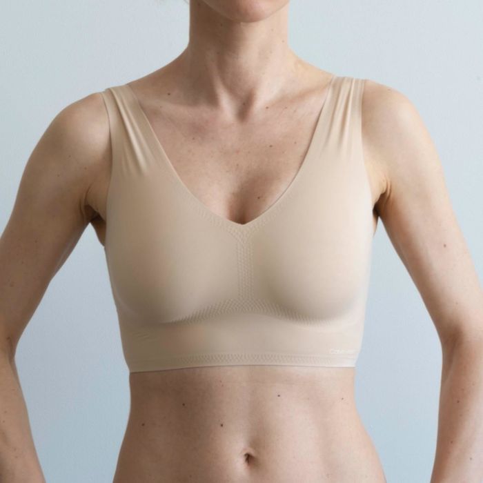 A reviewer is pictured wearing a tan bralette, front view