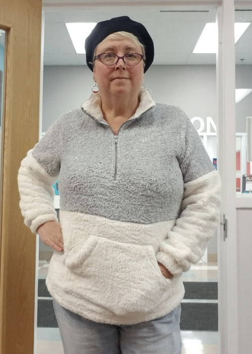 reviewer models a cozy pullover in white and grey tones