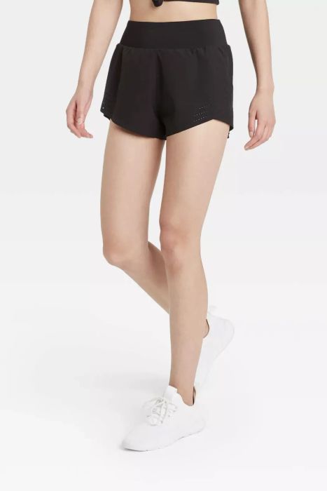 A model in black athletic shorts and white tennis sneakers.