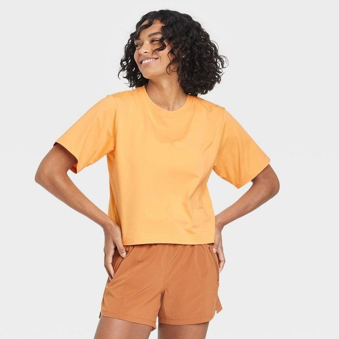 Model wearing the peach orange cropped cotton short-sleeve top