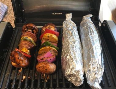 a reviewer's photo showing kebabs and corn cooking on the grill