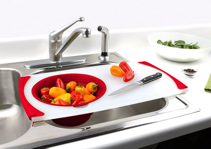 A white and red cutting board with a built-in strainer for added convenience.