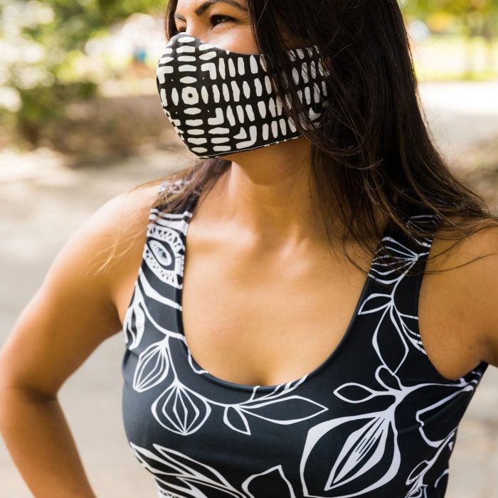 A model showcasing a black and white floral sports crop top paired with a matching black and white striped mask.