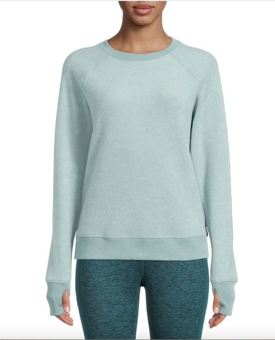 A person wearing an aqua green pullover and matching green leggings