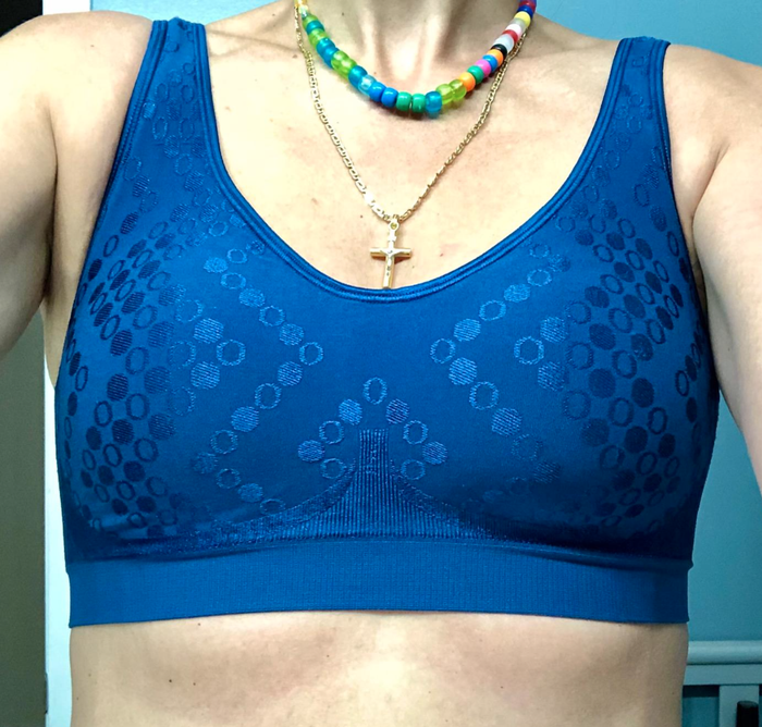 A person wearing a patterned sports bra paired with two beaded necklaces and a cross pendant. No names are mentioned.