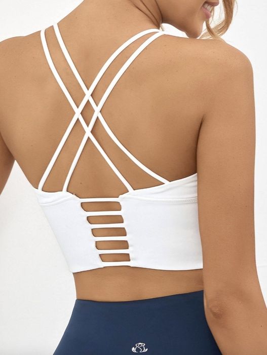 A person showing the back view of a strappy sports bra paired with blue leggings
