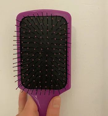 a reviewer's after photo displaying the same hairbrush now spotlessly clean