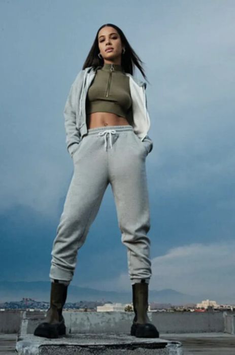 A model showcasing a gray coordinated sweatpants and zip-up hoodie paired with a green athletic top