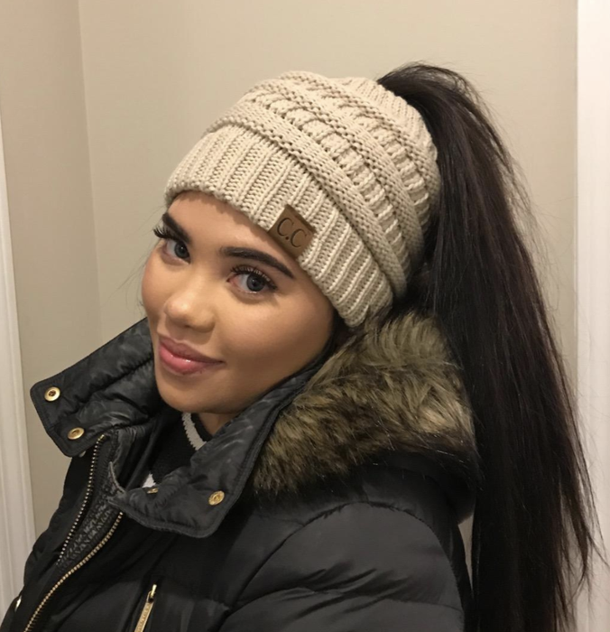 A reviewer models a hat while showcasing a ponytail.