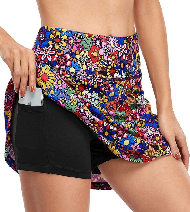 close-up of a model wearing the floral skort and placing a phone into one of the hidden pockets