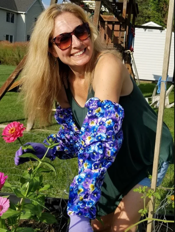 A woman enjoying her time in the garden, dressed in a green top and floral gloves, radiating positivity. Perfect for any gardening enthusiast.