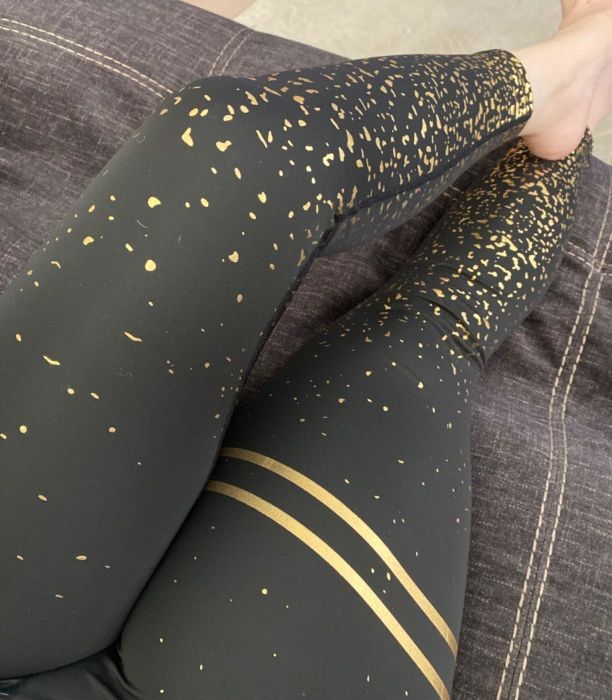 A reviewer showcases a pair of stylish black and gold leggings, making a bold fashion statement.