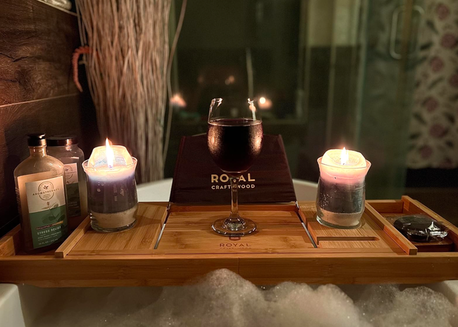 A bathtub tray holding candles, a drink, and bath products, creating the perfect serene ambiance.