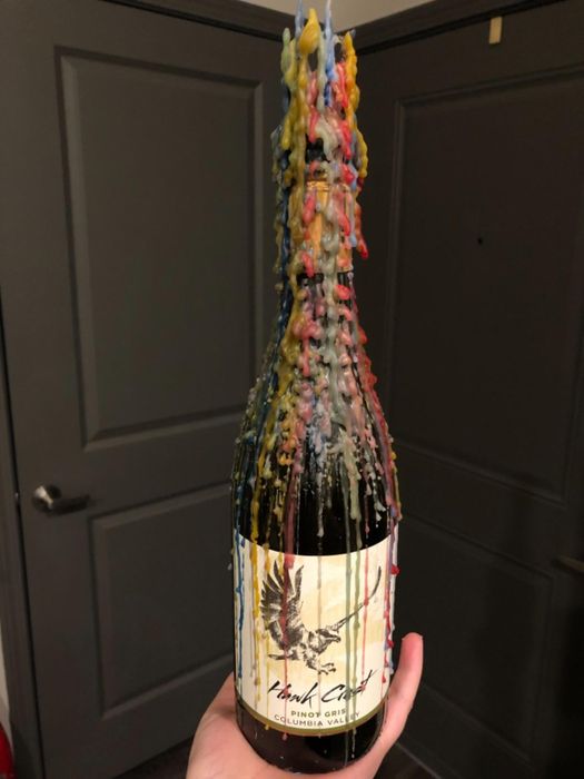 A hand gracefully holding a champagne bottle adorned with elegant wax drips.