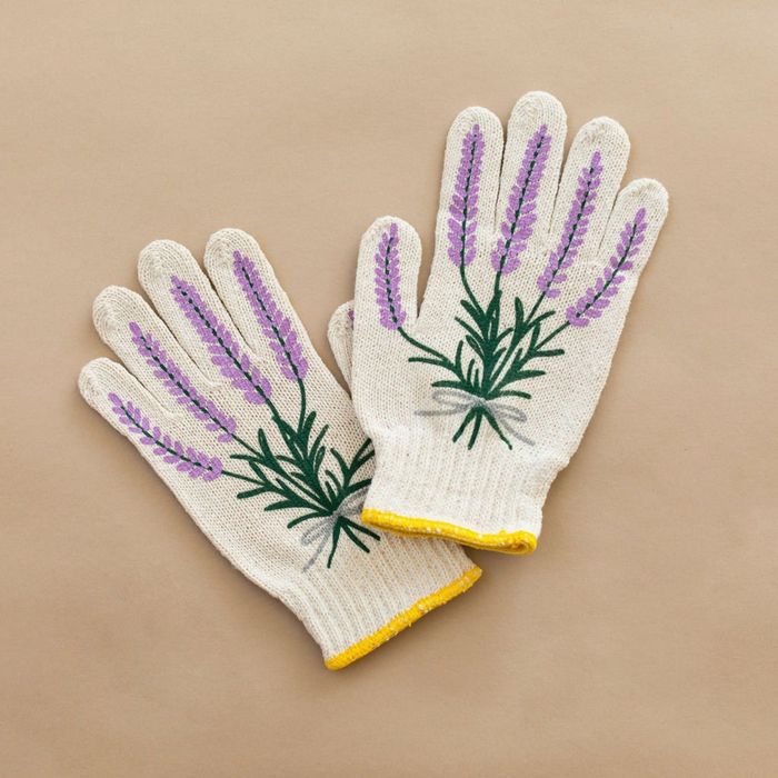 A pair of gloves featuring embroidered lavender on the back, placed against a solid backdrop for display in a shopping setting.
