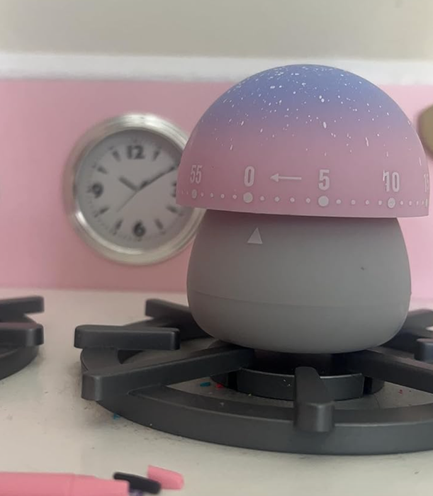 A small mushroom timer with a soft gray base, topped with a pink and purple cap, and featuring numbers for easy tracking of time.