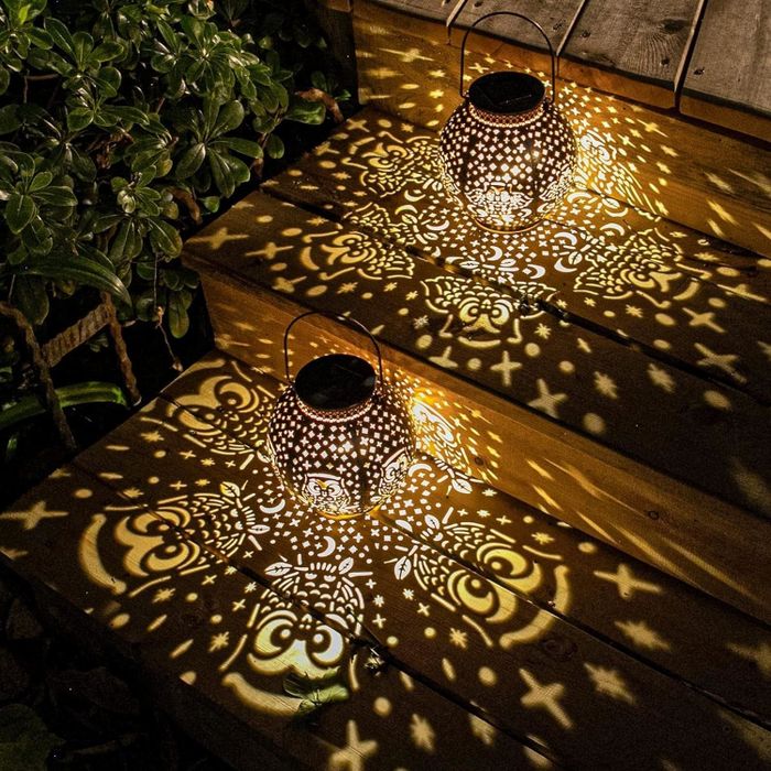 Two decorative lanterns casting beautiful patterned light across wooden steps at night.